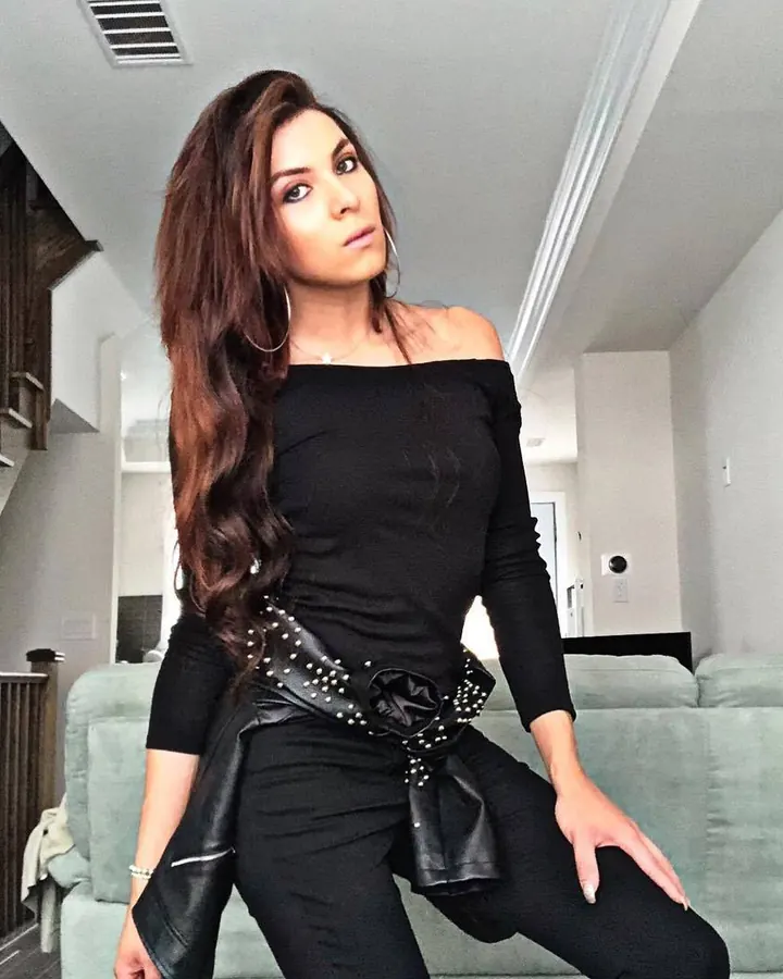 Femme en haut noir, poitrine mise en valeur, regardant vers l'appareil.