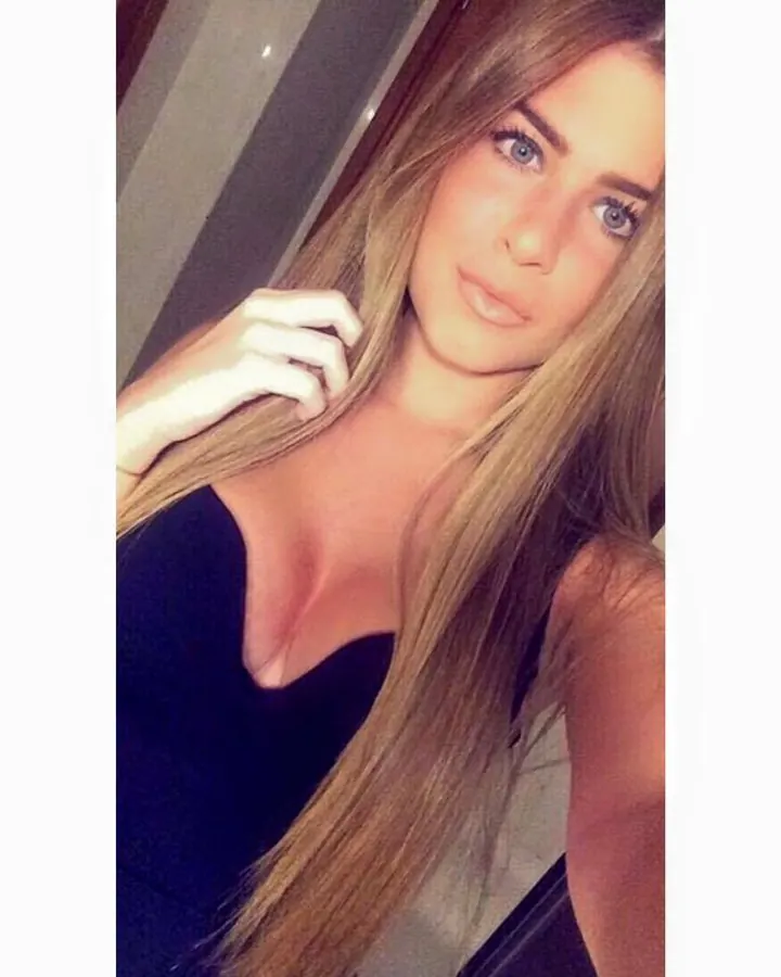 Femme blonde en haut noir, posant en selfie, regardant l'appareil