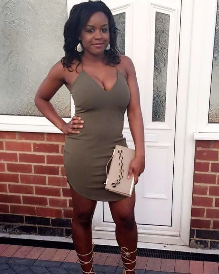 Femme aux cheveux bruns-noirs en robe verte, debout devant une porte blanche, regardant l'appareil avec un sourire chaleureux.