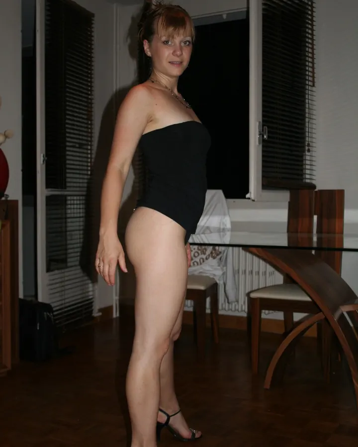 Femme aux cheveux châtains portant un haut noir, assise sur un canapé